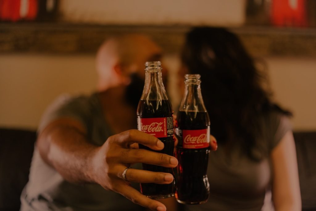 A man and a woman holding Coca-Cola bottles